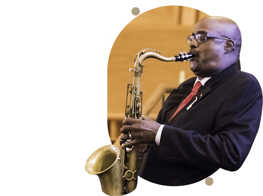 A man playing the saxophone in front of a green background.