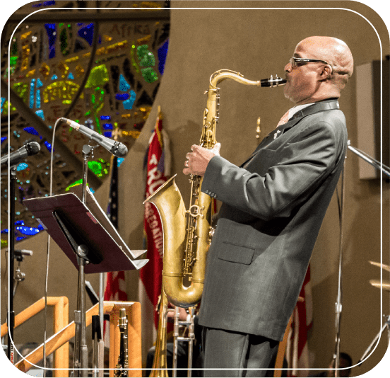 A man in a suit and sunglasses playing the saxophone.